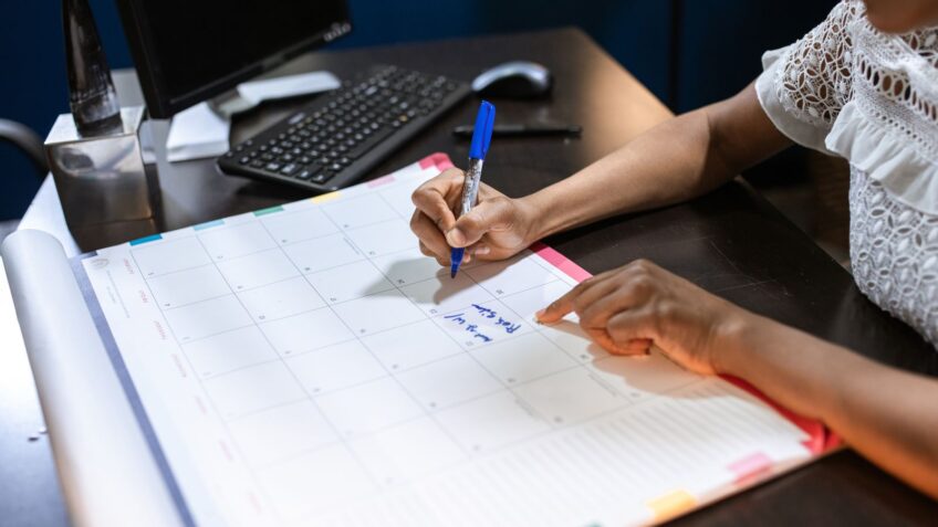 Person marking a desk calendar to plan the best time to buy