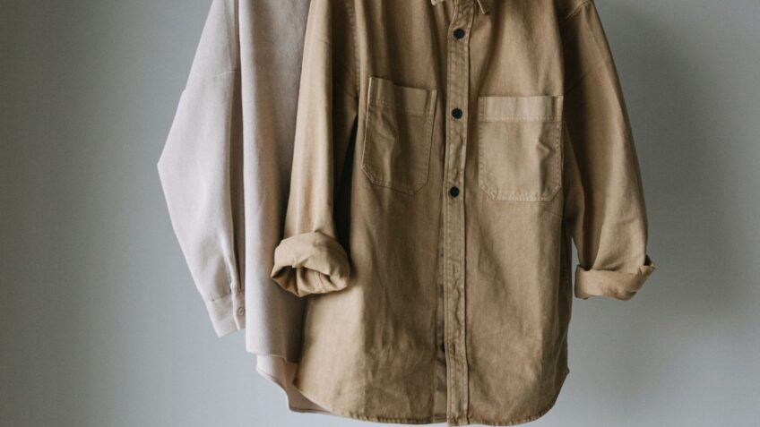 Neutral-toned shirts hanging on a rack as part of a fall capsule wardrobe