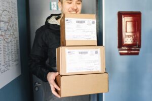 Delivery worker holding several packages indoors