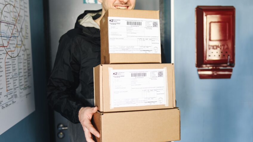 Delivery worker holding several packages indoors