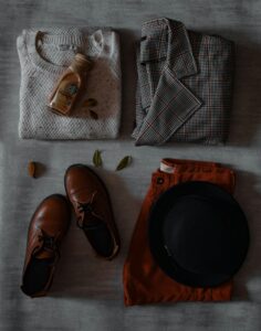 Cozy fall clothing including a sweater and hat laid out on a bed