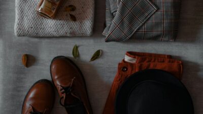 Cozy fall clothing including a sweater and hat laid out on a bed