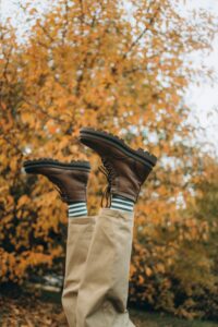 Brown boots paired with a fall outfit against autumn leaves