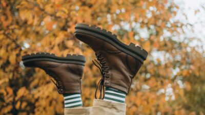 Brown boots paired with a fall outfit against autumn leaves
