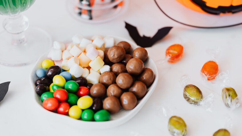 Festive Halloween candy assortment with chocolate, marshmallows, and jack-o'-lantern decor