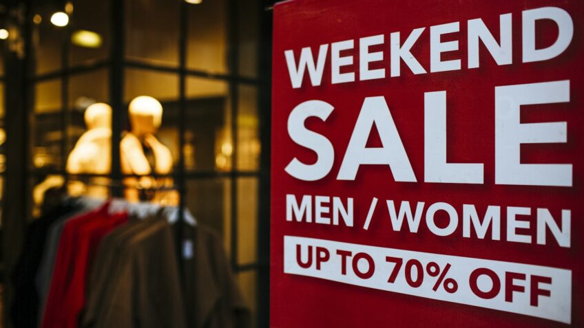 Weekend sale signage displayed in a store window for Labor Day
