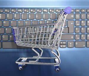 Miniature shopping cart on a laptop keyboard symbolizing online shopping and e-commerce