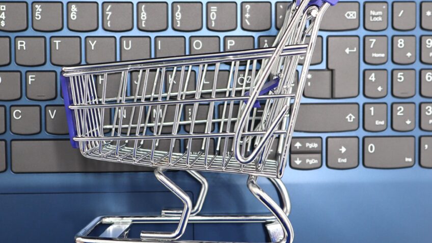 Miniature shopping cart on a laptop keyboard symbolizing online shopping and e-commerce