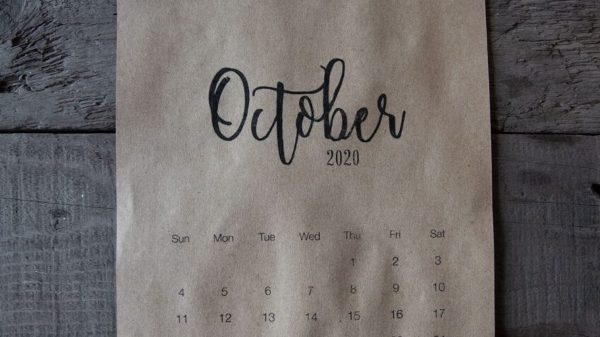 October calendar page on a wooden surface representing upcoming fall sales