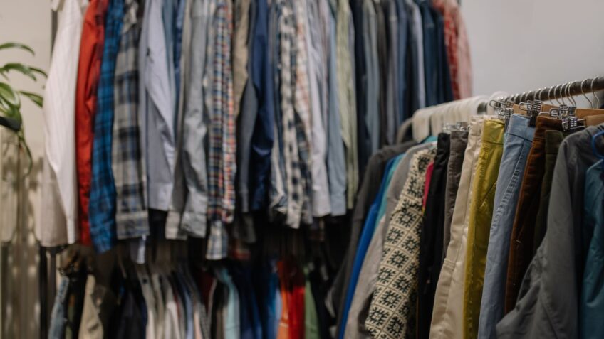 Assorted clothing hanging on racks in a thrift shop