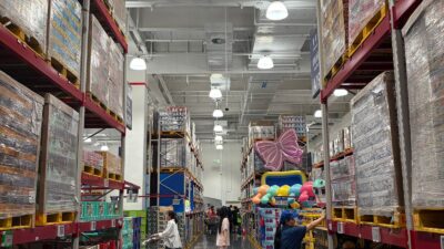 Shoppers browsing a warehouse club store aisle stocked with bulk products